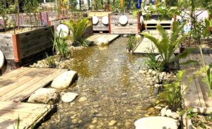 Ein Foto einer temporären Installation von ProBach auf der Klimabiennale. Es wurde mit Paletten und Wasserpumpen ein Abschnitt von Wiens Bächen simuliert